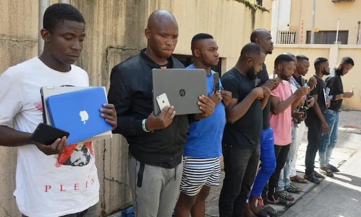 Yahoo Boys operating online scams, symbolizing Nigeria’s cybercrime network and its global impact through romance fraud and dark rituals.