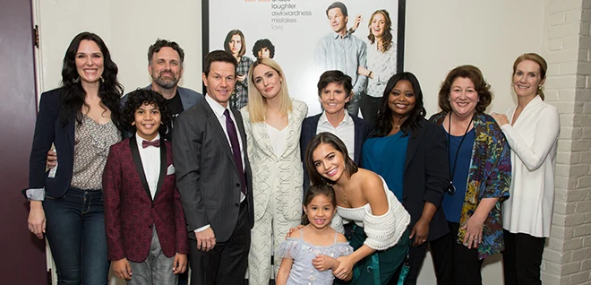 A warm family moment inspired by the movie Instant Family, showing adoptive parents bonding with children in a cozy living room setting, symbolizing real-life adoption stories.