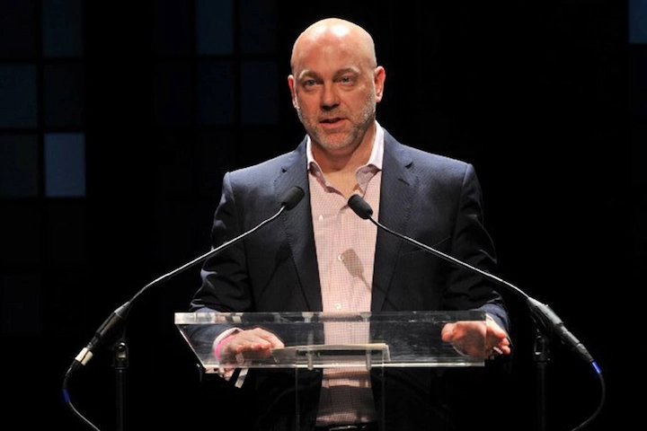 Donald Mullen speaking at a financial event in a dark suit