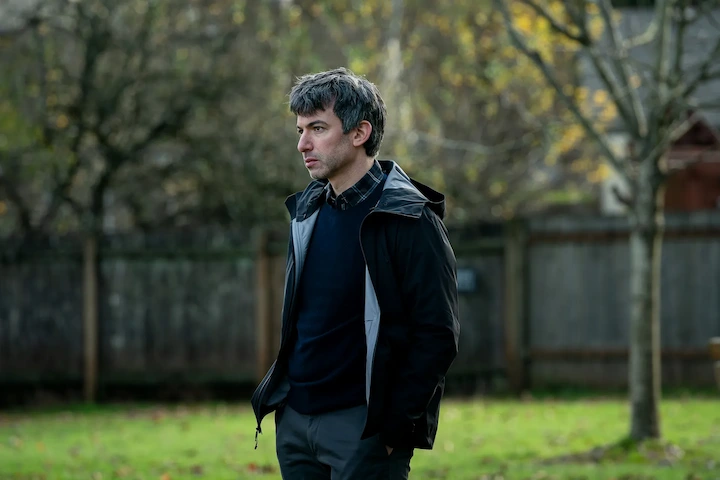 Nathan Fielder standing outdoors in casual clothing, reflecting during a scene from The Rehearsal.