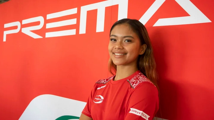 Bianca Bustamante smiles in Prema Racing uniform in front of red sponsor backdrop