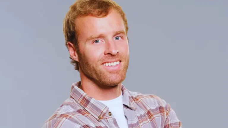 Smiling portrait of Biggy Bailey in a plaid shirt on a gray background.