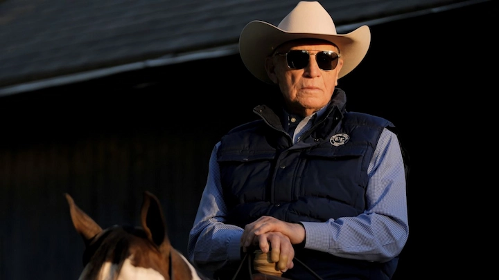 D. Wayne Lukas riding a horse wearing a cowboy hat and sunglasses during morning training session.