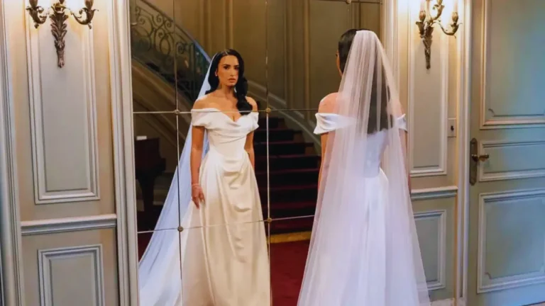 Demi Lovato in her Vivienne Westwood wedding gown, standing in front of a mirror in an elegant room.