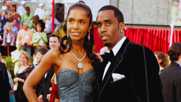 Sean Combs and a woman pose on the red carpet at a formal event with a crowd in the background.