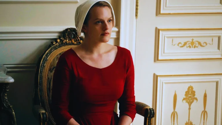 Elisabeth Moss as June Osborne wearing a red dress and white bonnet in The Handmaid’s Tale.