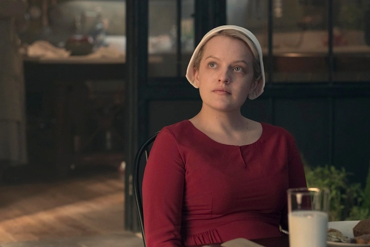 June Osborne, played by Elisabeth Moss, seated at a dinner table in The Handmaid’s Tale.