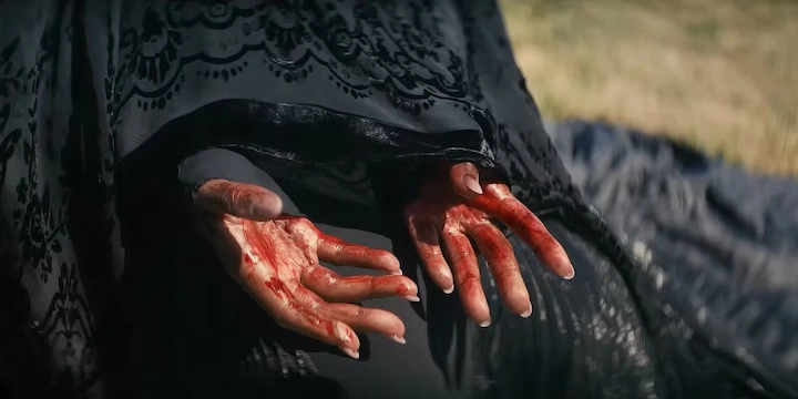 Close-up of bloody hands in black lace sleeves from The Woman in the Yard psychological horror film.