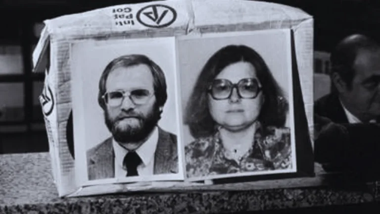 Black and white image of James and LeAnn Lewis displayed during a press conference, with their faces shown on a cardboard prop.