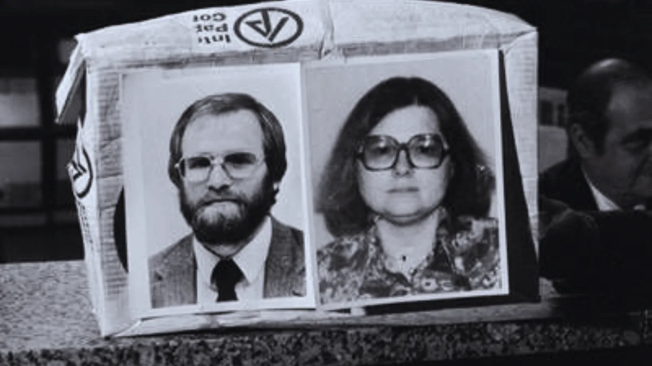 Black and white image of James and LeAnn Lewis displayed during a press conference, with their faces shown on a cardboard prop.
