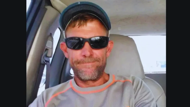 Marc Bruss wearing sunglasses and a cap while sitting inside a vehicle.