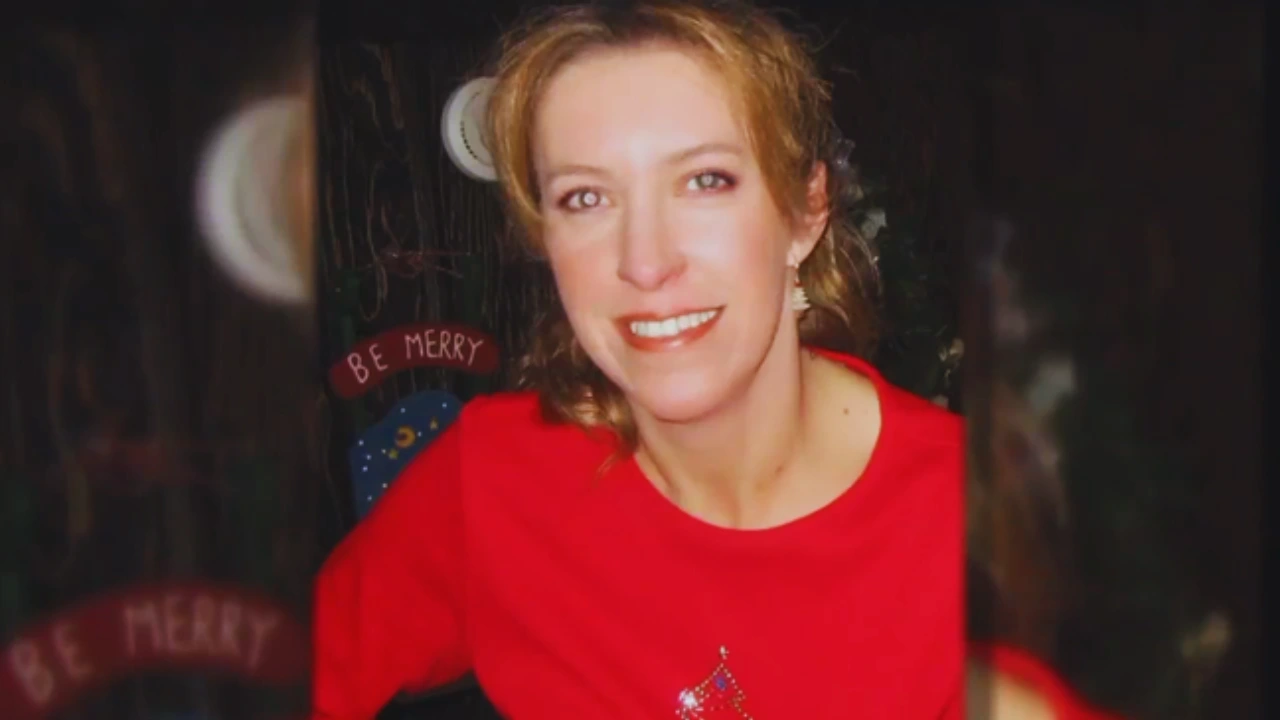 Michelle Mockbee smiling in a red holiday sweater with "Be Merry" decor in the background.