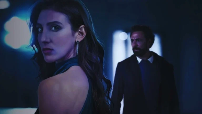 Julia looks over her shoulder suspiciously while her husband watches from the shadows in Secret Life of the Surgeon’s Wife.