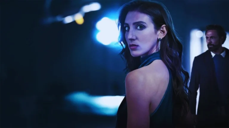 Woman in a dark dress looks back anxiously as a man stands behind her in a suspenseful scene.