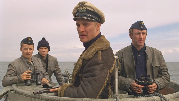 U-571 movie scene with uniformed men looking out from submarine deck during daylight.