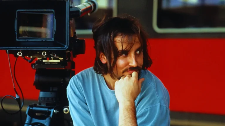 Young Richard Linklater sitting beside a vintage film camera during production.