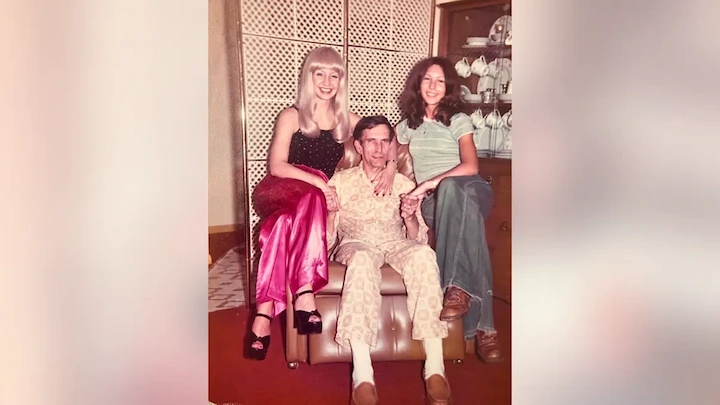 Vintage photo of Adrienne Pollack seated with her father and sister in a home setting, early 1970s.