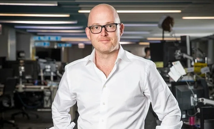 Andrew Sieja in a modern office setting, wearing glasses and a white shirt, tech entrepreneur