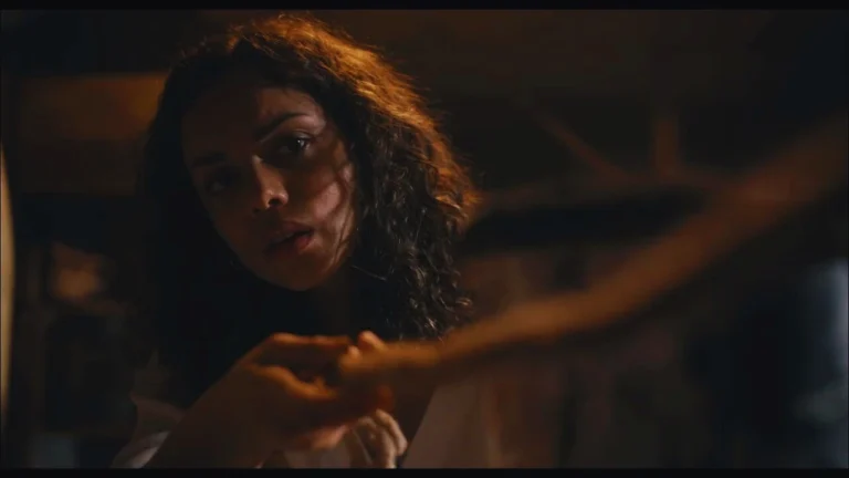 Tess Marshall cautiously exploring basement in Barbarian movie scene.