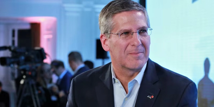 Bob Moritz at a business event, wearing a suit and glasses, featured in a net worth and career article.
