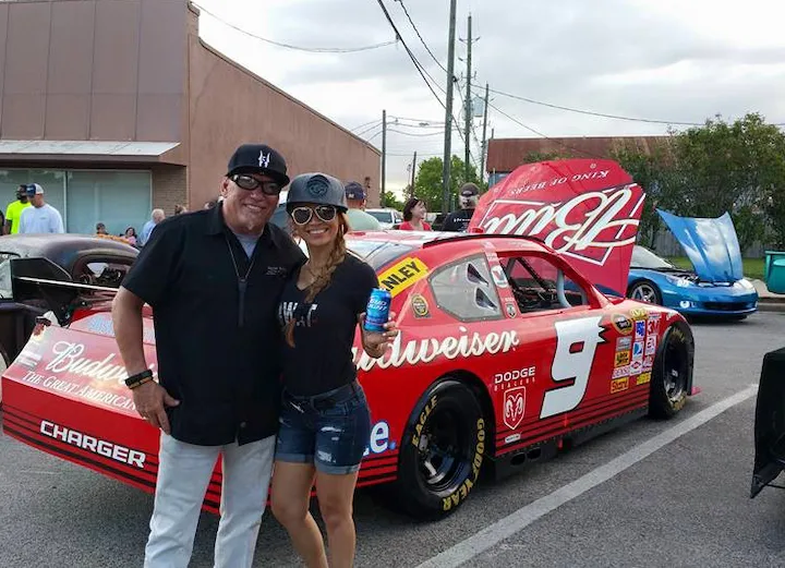 Daisy Wells and companion at car show with red Budweiser Dodge Charger race car in Texas