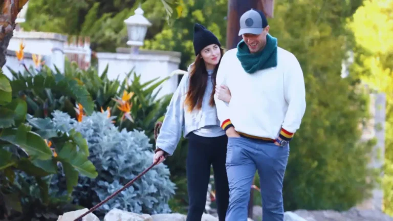 Dakota Johnson and Chris Martin walking their dog outdoors, wearing casual clothes.
