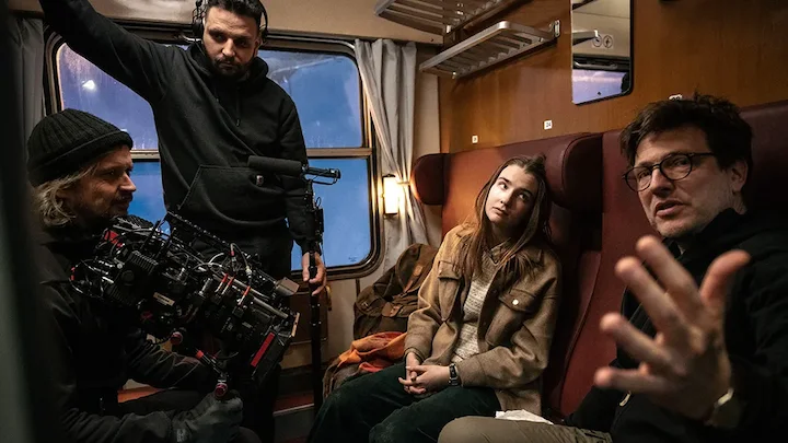 Cast and crew film an intense train scene from Families Like Ours featuring Laura in a moving cabin.
