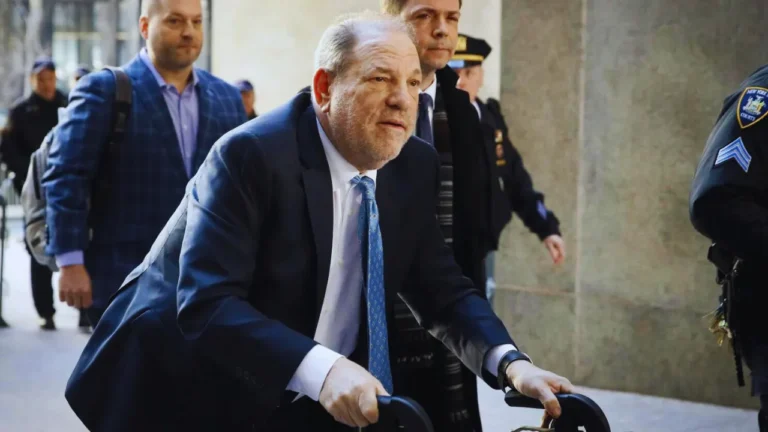 Harvey Weinstein arrives at court using a walker, surrounded by security and legal team members.