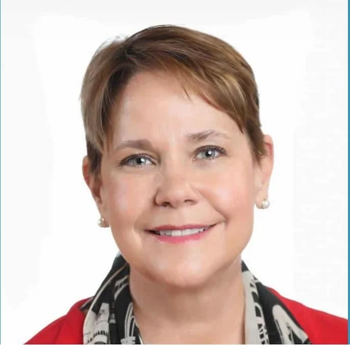 Close-up of Jodie Barnard smiling, wearing a red top and patterned scarf, featured in 2025 biography.
