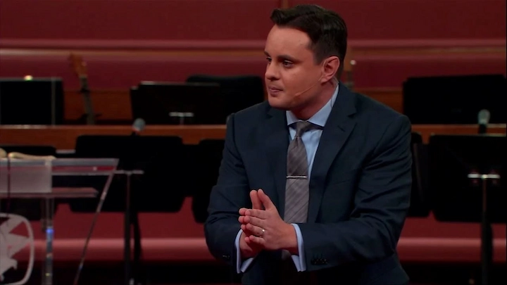 Josh Rosenstern speaking at church in a suit during a live broadcast on SonLife Broadcasting Network