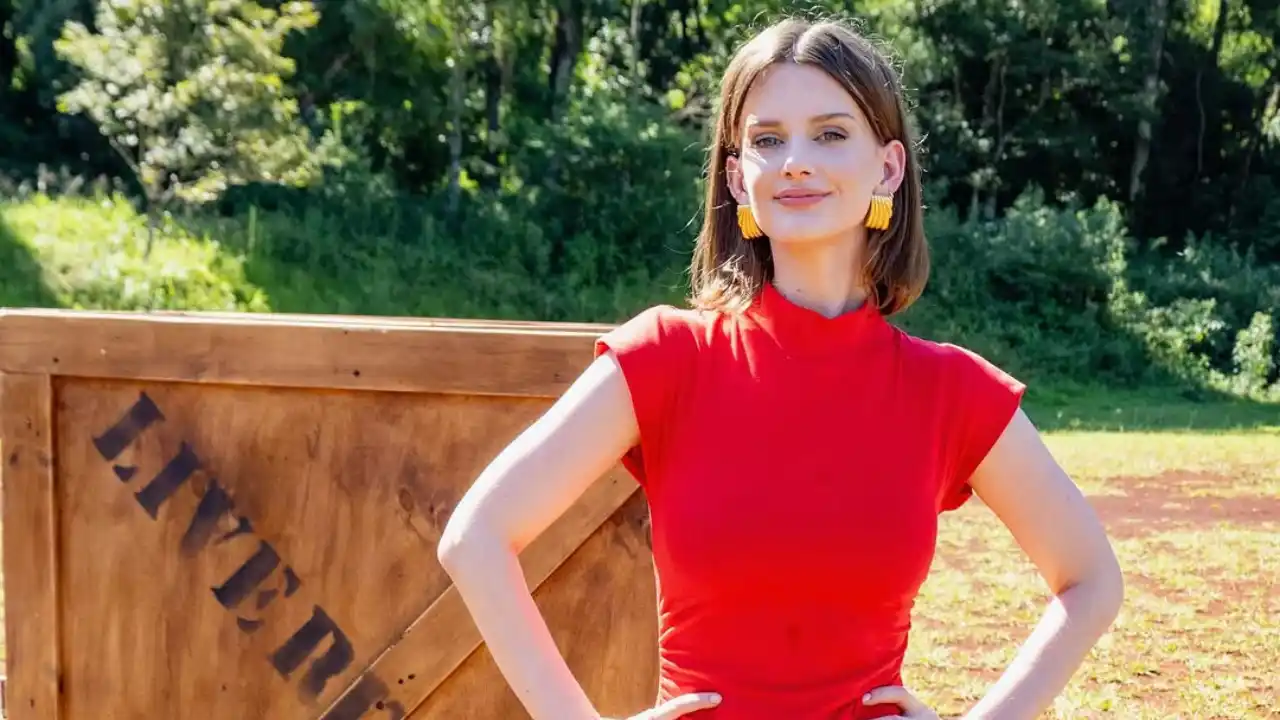 Kathryn Cavender outdoors smiling in red dress near a wooden crate marked "LIVE".