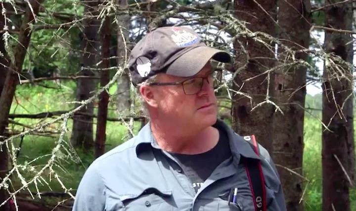 Laird Niven in forest setting wearing cap and glasses during Curse of Oak Island archaeology work