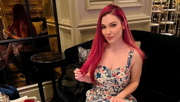 Lily Lou sitting in a cafe wearing a floral dress, featured in her 2025 net worth and career story article