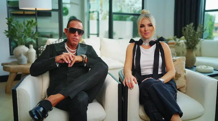Michael and Jules Iavarone sitting in a modern living room, dressed in chic black and white fashion.