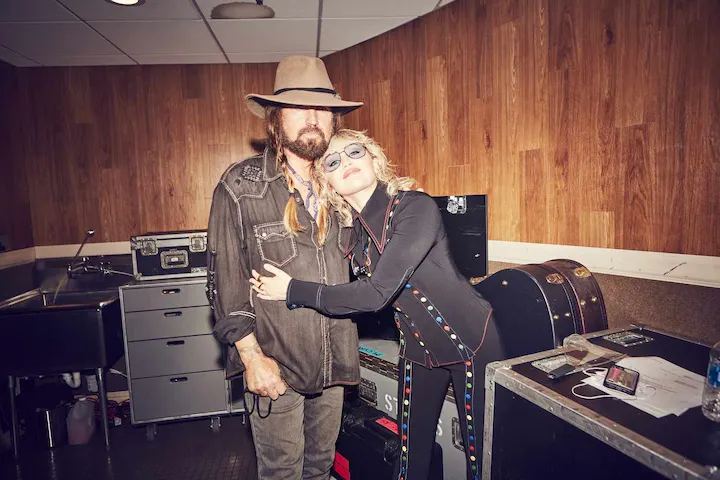 Miley Cyrus embraces Billy Ray Cyrus backstage, reflecting their renewed bond and emotional growth.