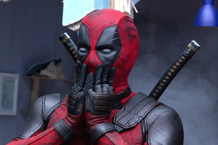 Deadpool in VR covers mouth with gloved hands, red-and-black suit detailed, katanas strapped on back.