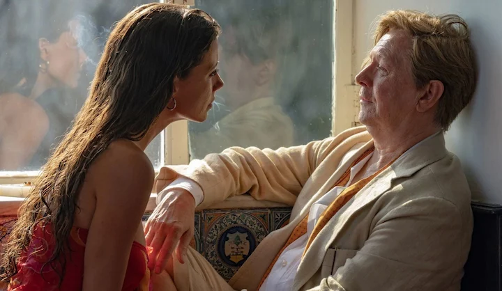 A woman with wet hair leans toward an older man on a sunlit ferry, reflecting intense emotion.