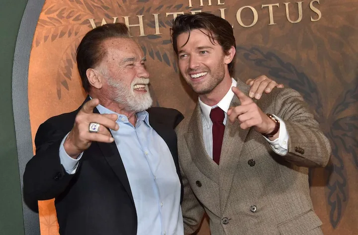 Arnold and Patrick Schwarzenegger laughing at White Lotus premiere red carpet.