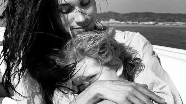 Meghan Markle hugs Princess Lilibet during a tender moment on a boat, windswept and smiling.