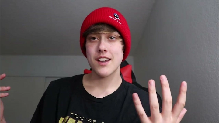 Raegan Beast wearing red beanie and black shirt, smiling and gesturing during a casual video chat