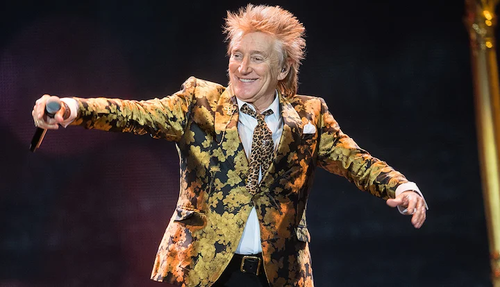Rod Stewart performing energetically on stage in a floral jacket, highlighting his Highgate roots and rock icon status.