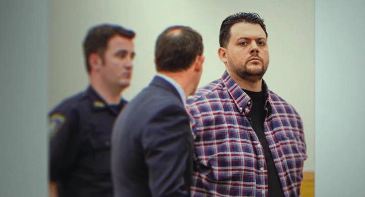 Anthony Strangis stands in court with his lawyer at his side and a police officer in the background.