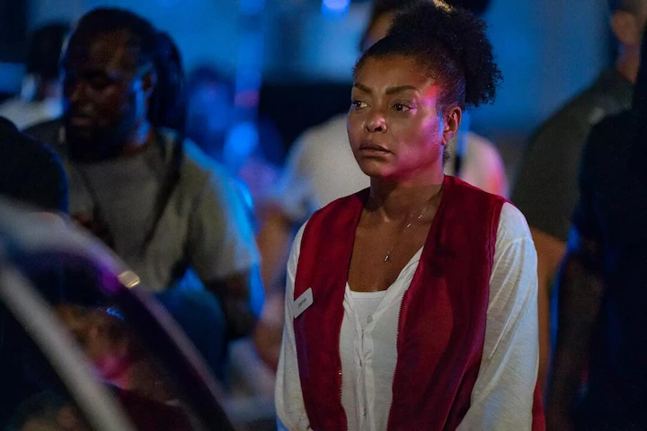 Janiyah Wiltkinson standing tense among a crowd outside the bank at night, lit by police lights.