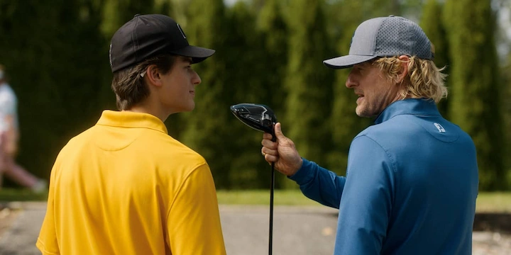 Owen Wilson coaching Peter Dager with a golf club during a golf scene in Apple TV+ series Stick.
