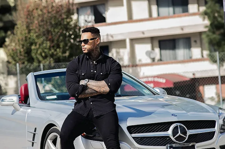 Jeff Logan poses confidently on a silver Mercedes, showcasing success and luxury lifestyle in 2025.